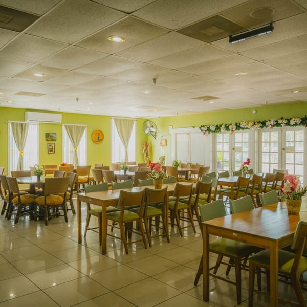 Spacious Nipa Hut Bar & Restaurant dining room with wooden tables, chairs, and light green walls.