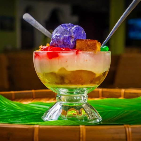 A vibrant Filipino Halo-Halo dessert in a glass, topped with purple ube ice cream and cake.